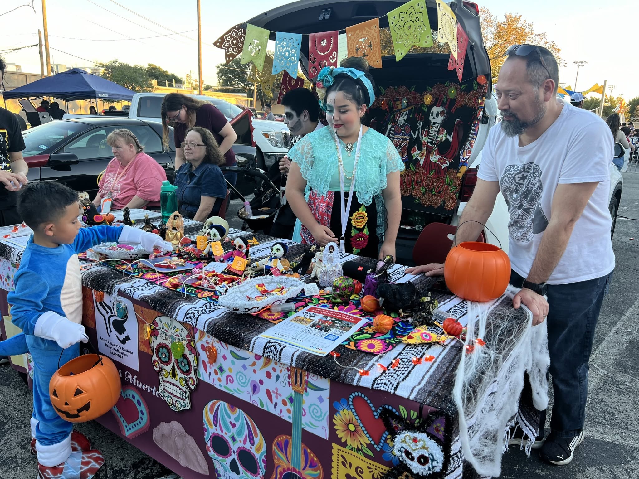 A colorful Day of the Dead booth with decorated skulls, papel picado banners, and festive crafts at an outdoor event.