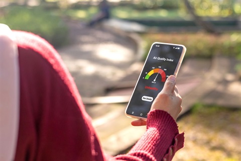 Woman outside looking at air quality forecast on her Phone