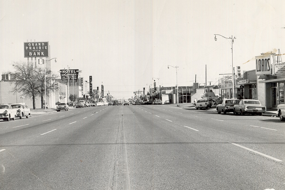 Old view of Main Street. Picture is in black and white. There are signs for Grand Prairie State Bank and Hotel Lennox.