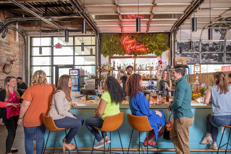 Several people sitting or standing at a bar at Firehouse Gastro Park