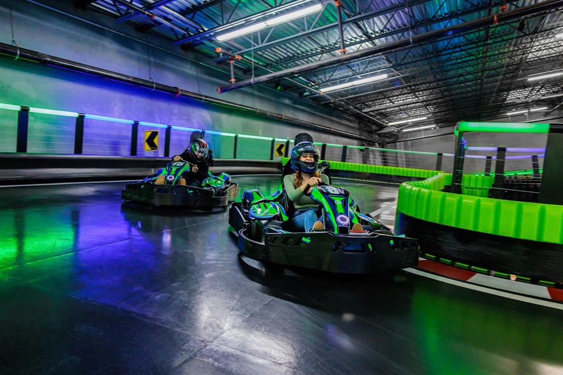 Three people driving karts at Andretti Indoor Karting
