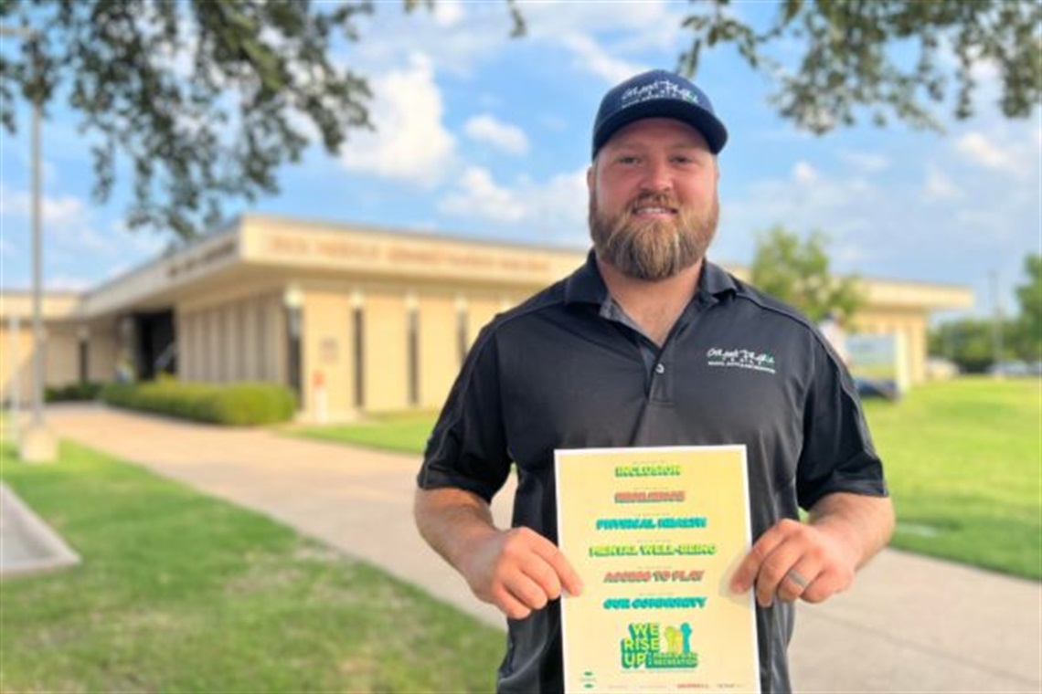 Grand Prairie Parks employee stands with message 