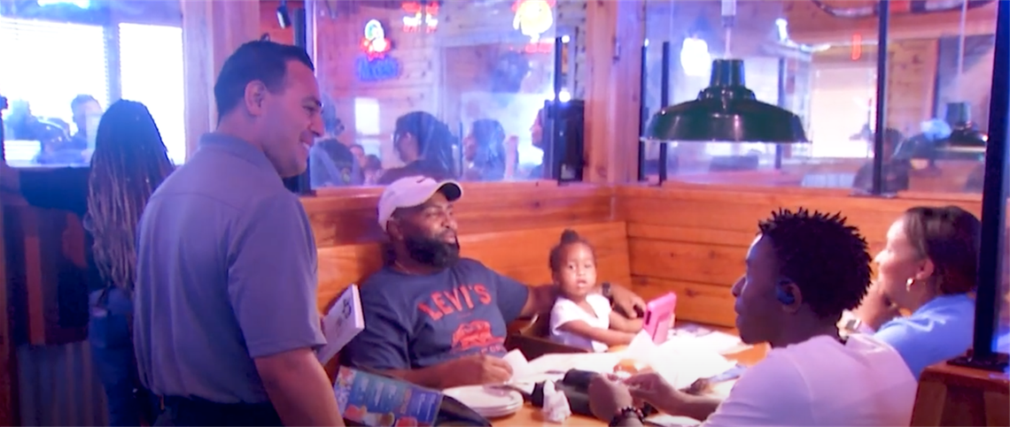 Family sitting at a table at Texas Roadhouse talking to their server