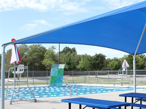 View of Bowles Outdoor Pool and the surrounding area, including picnic tables, lifeguard stands and a rock climbing wall