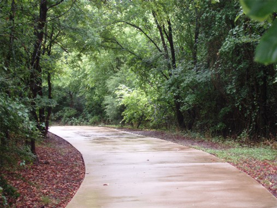 Paved trail at Fish Creek Linear Park with trees on either side