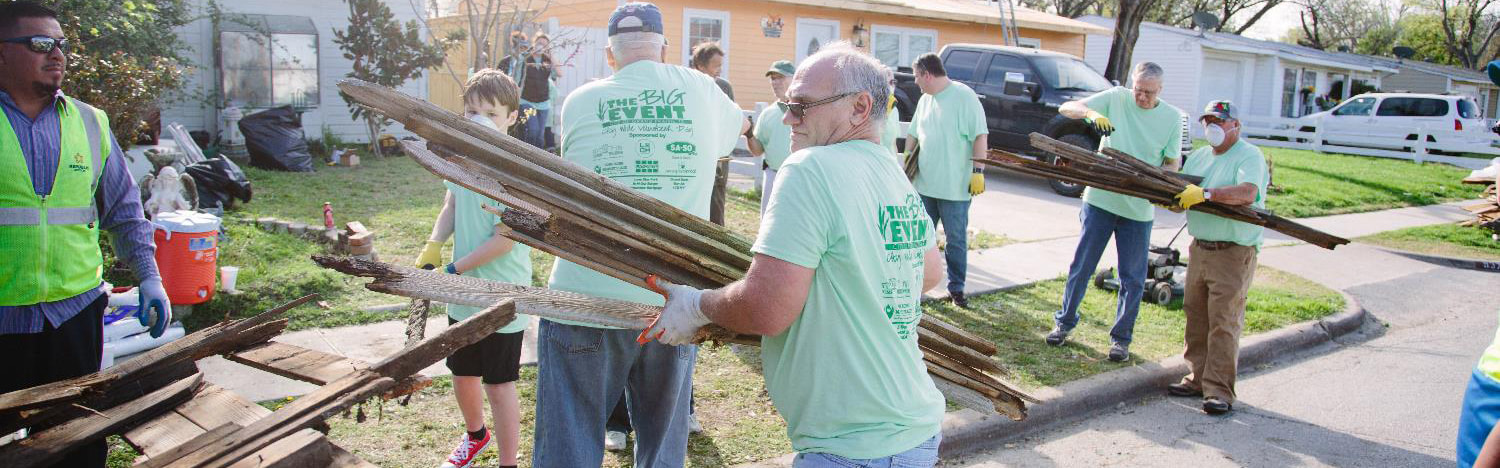 People carrying old fence posts and putting them in a pile